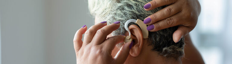 A woman adjusts her hearing aid.