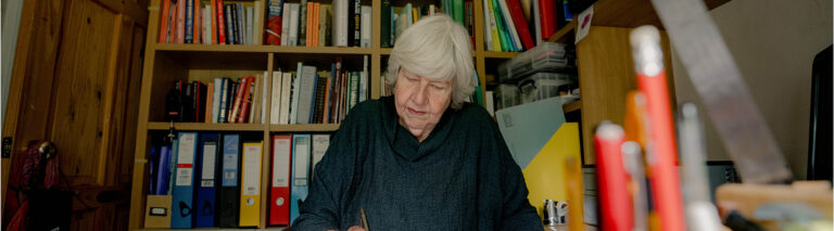 Anne Youngson writes at her desk, with a library of books behind her